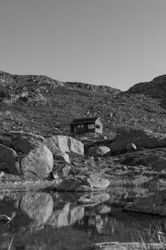 Black and white view of a solitary cabin amidst rocky mountains in Vestland, Norway.