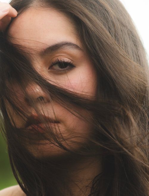 Free Close-up portrait of a woman with lush, flowing hair gently blown by the wind. Stock Photo