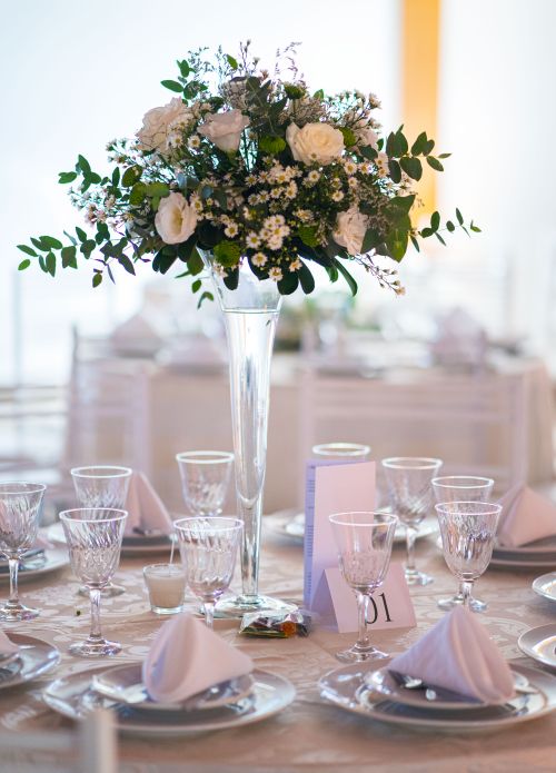 Free Beautiful wedding table setting with a tall floral centerpiece and elegant tableware, ready for a special occasion. Stock Photo