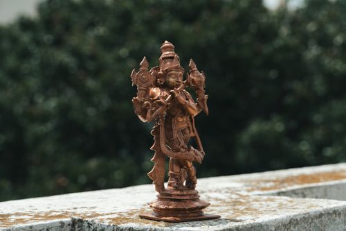 Free Detailed bronze statue of a Hindu deity with lush greenery. Captured outdoors in Bengaluru, India. Stock Photo