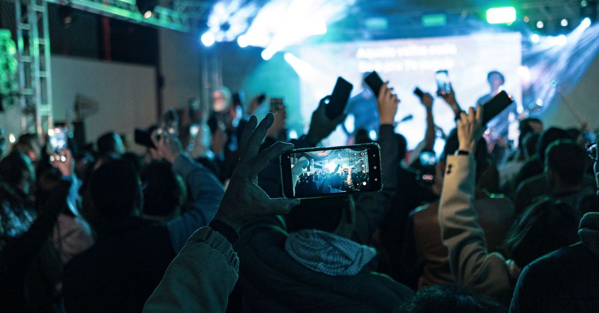 person recording breaking news on smartphone in crowd