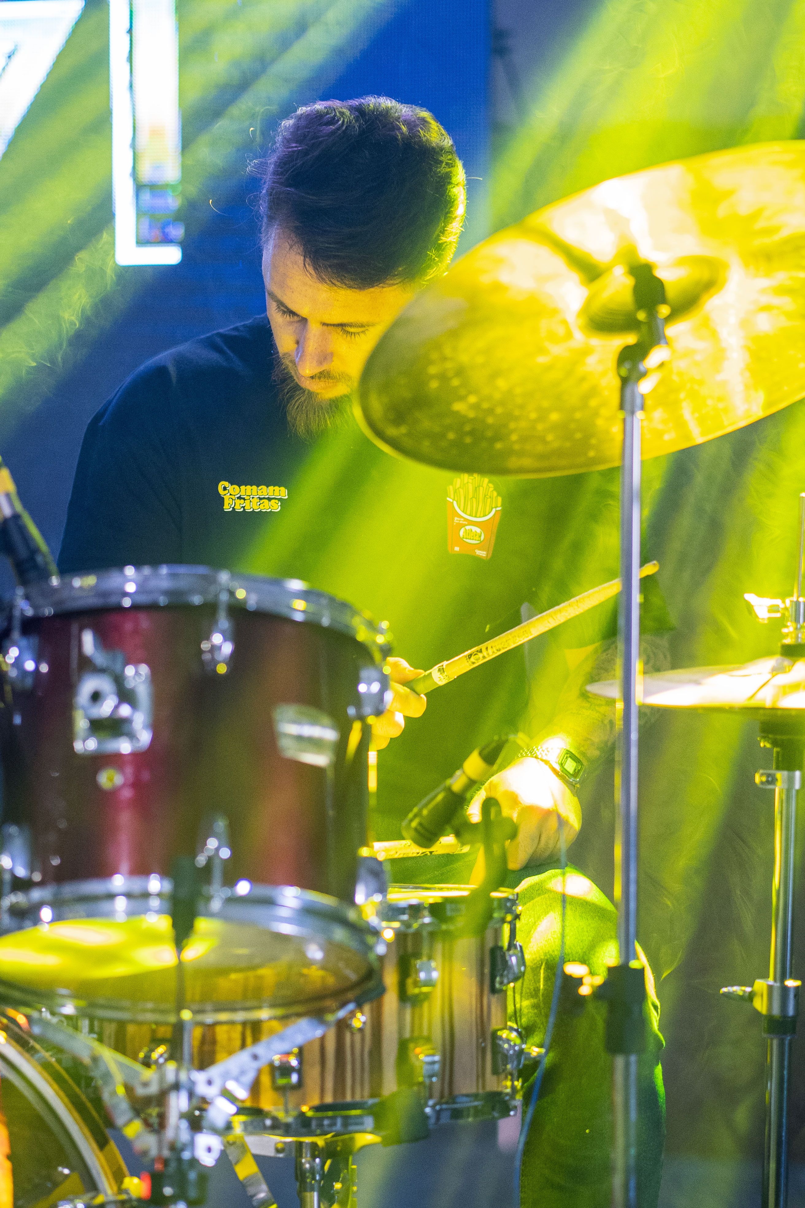Drummer performing live under dramatic stage lighting, creating an energetic atmosphere.