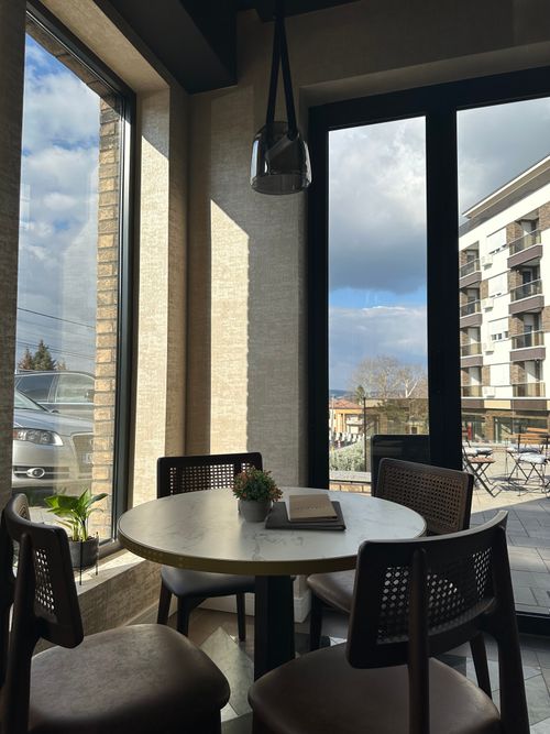 Free Inviting cafe table with large windows and cityscape view. Perfect for relaxation. Stock Photo