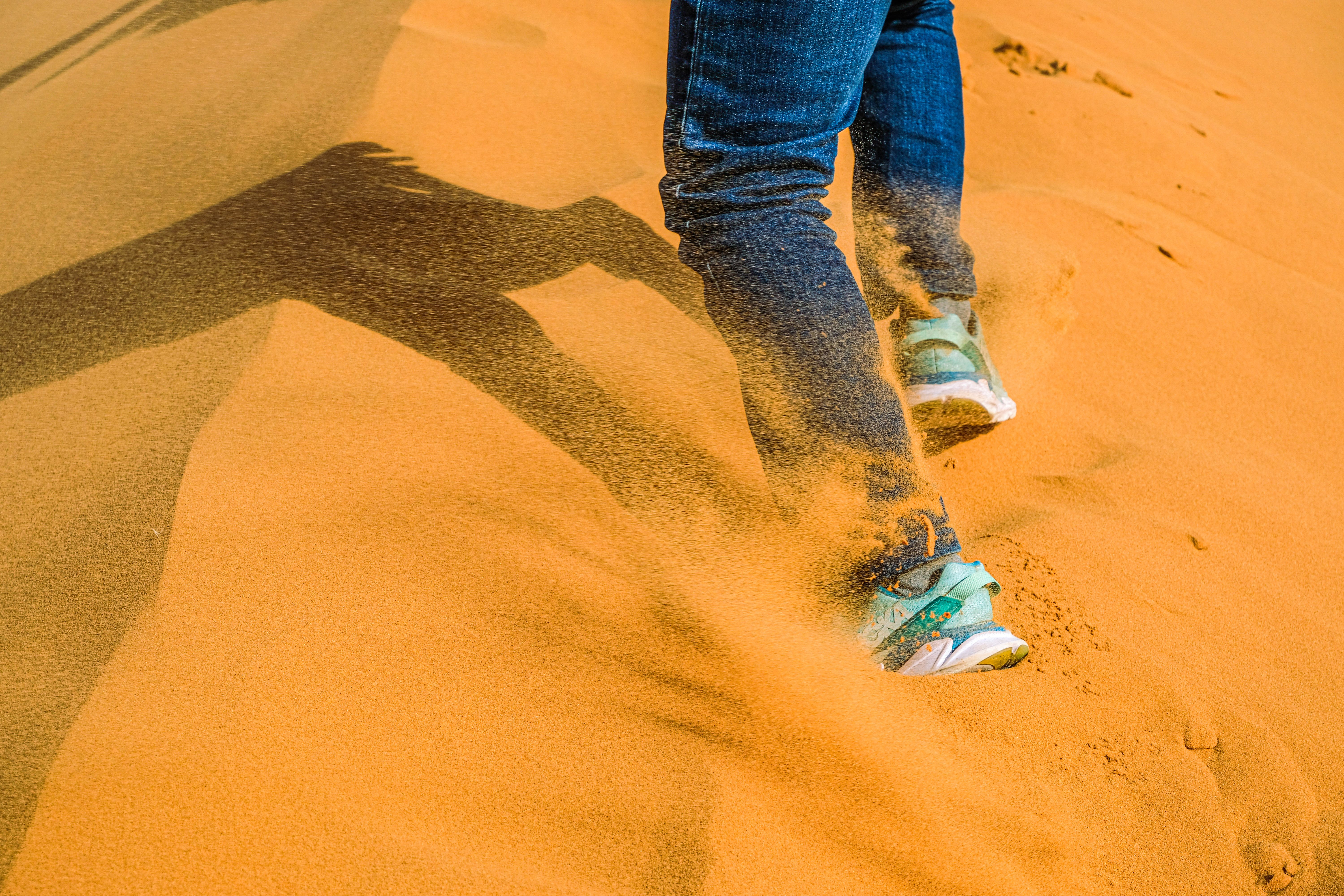 A traveler walking through desert sand dunes