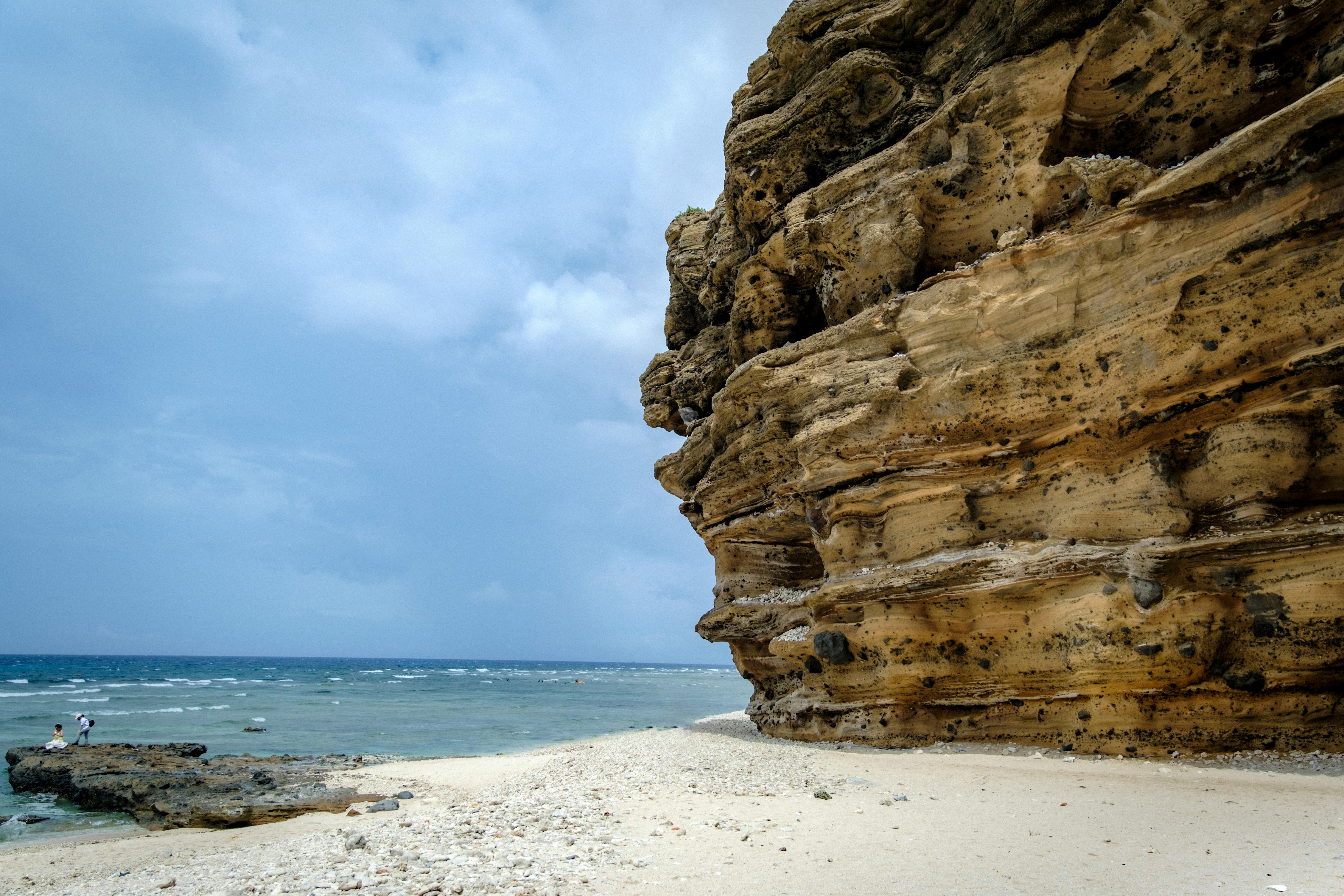 Stunning rocky cliff by the tranquil ocean on a cloudy day, perfect for travel inspiration.