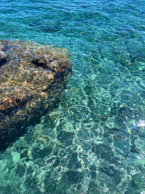 Free Crystal clear turquoise sea water with rocks visible underneath. Serene and refreshing seascape. Stock Photo