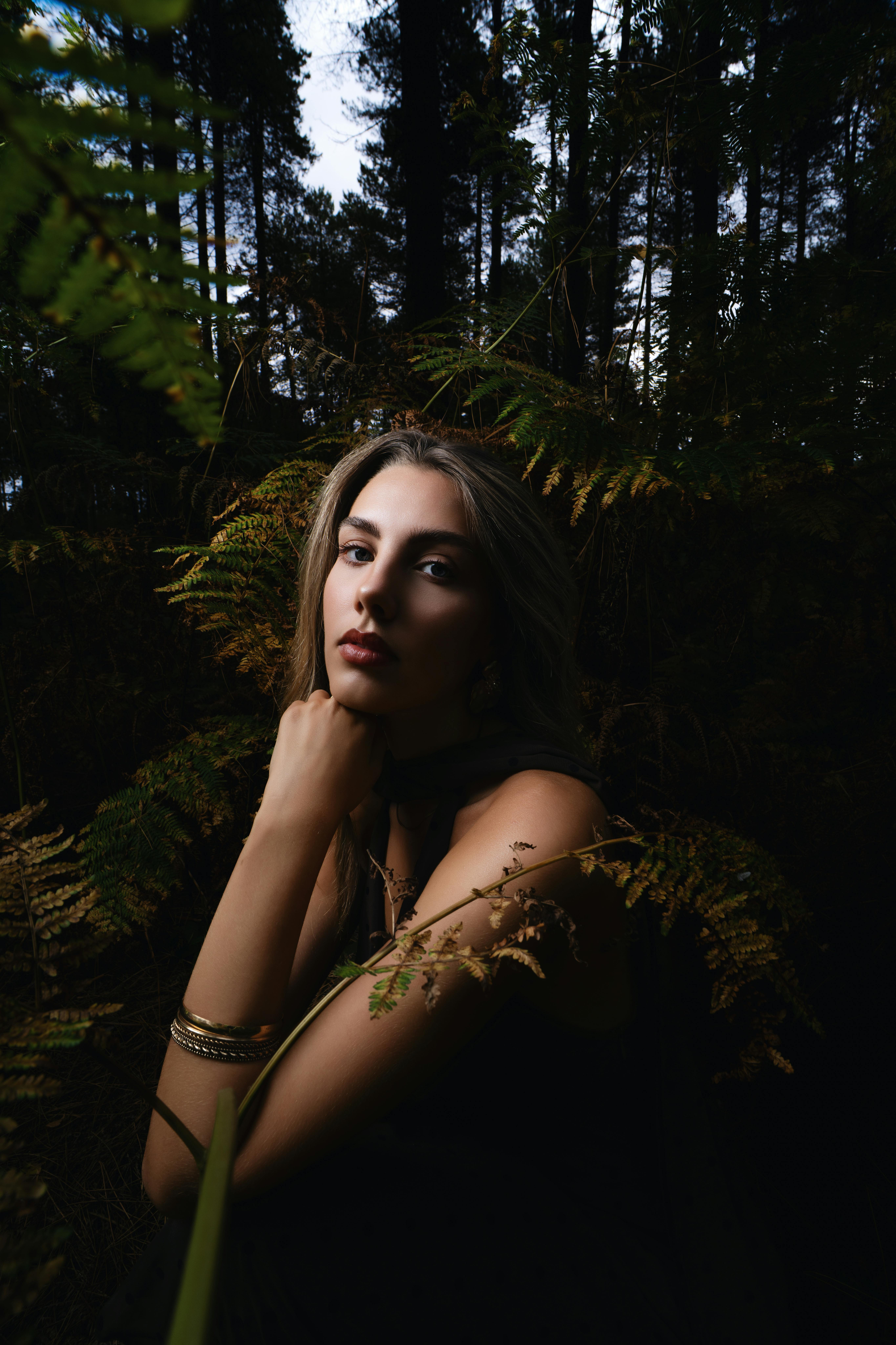 Moody portrait of a woman in a forest, blending contemporary fashion with natural beauty.