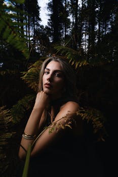 Moody portrait of a woman in a forest, blending contemporary fashion with natural beauty.