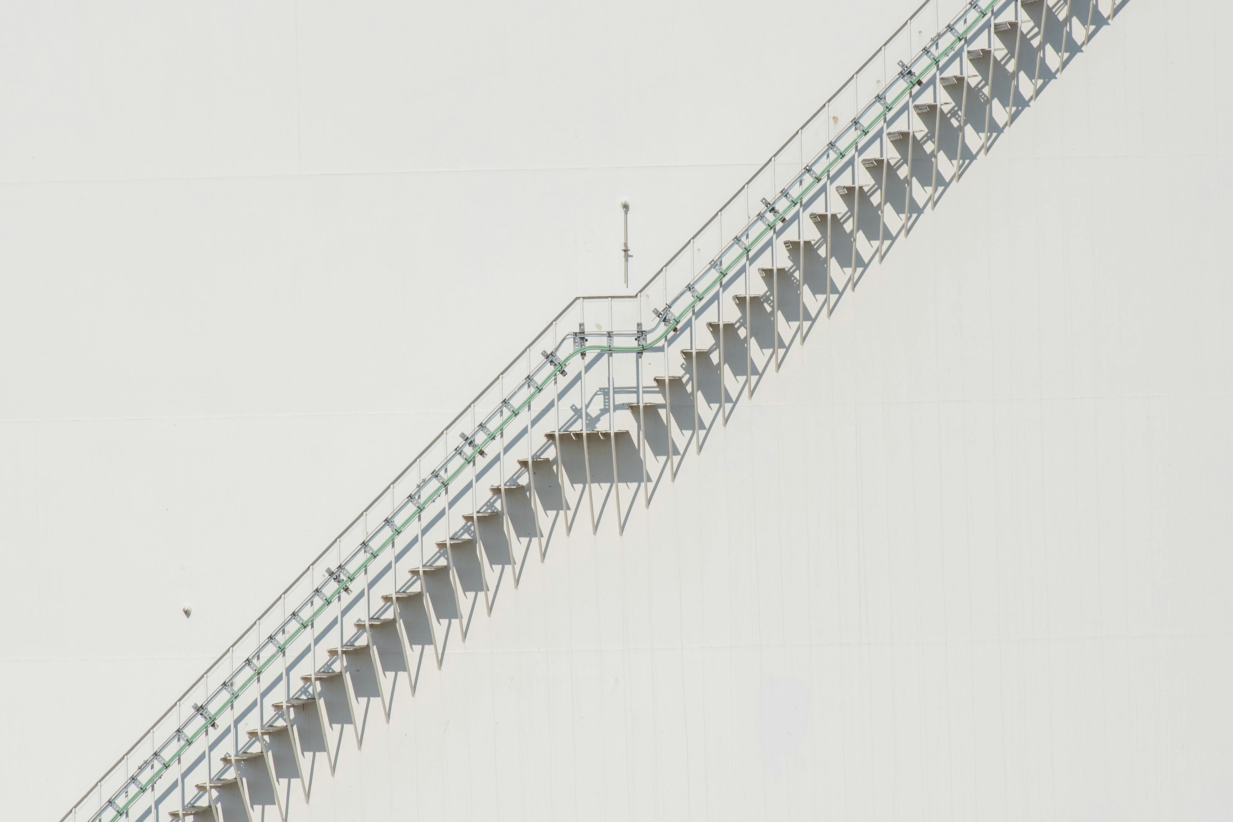 Free A clean, minimalistic, industrial staircase casting geometric shadows on a white surface. Stock Photo