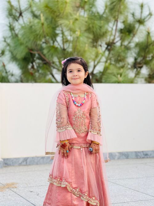 Free Cute girl wearing traditional pink dress, posing outdoors. Perfect for cultural and festive themes. Stock Photo