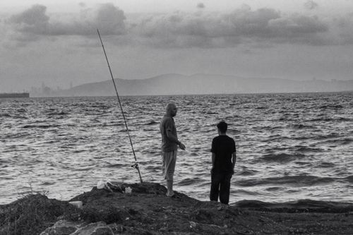 Free Two men fishing by the sea in Yalova, Türkiye, evoking a calm and serene coastal atmosphere. Stock Photo
