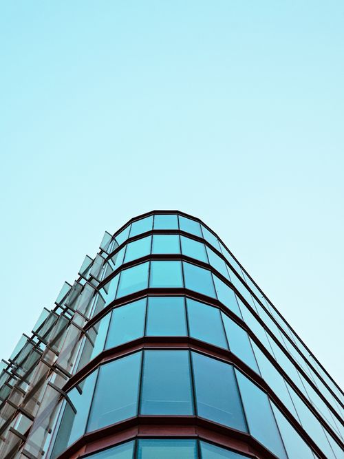 Free A contemporary glass building with blue reflections shot from below against a clear sky. Stock Photo