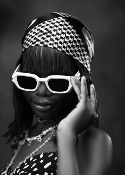 Free Black and white portrait of a woman with sunglasses and a patterned scarf. Stock Photo