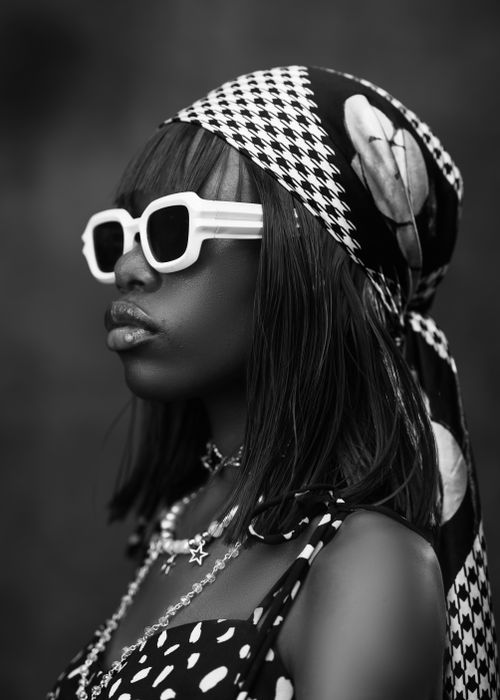 Free Elegant black and white portrait of a stylish woman in retro attire with bold sunglasses and accessories. Stock Photo