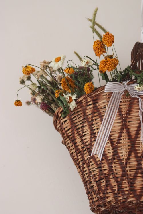Free A charming arrangement of dried wildflowers in a rustic basket with a striped ribbon. Stock Photo