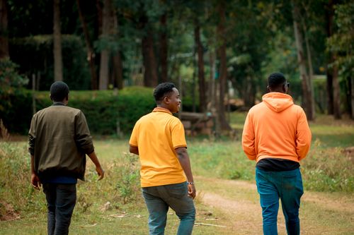 Free Three men walking on a garden path in Homa Bay, Kenya. Casual and serene outdoor scene. Stock Photo