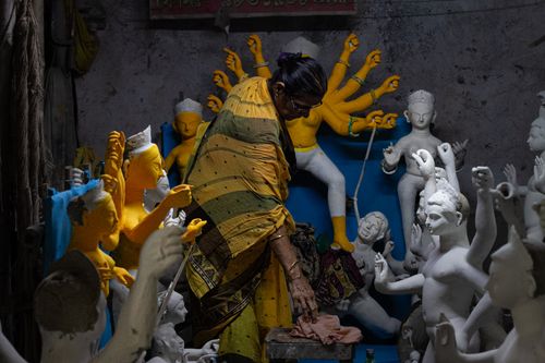 Free An artisan carefully molds clay Hindu deities in a traditional workshop setting. Stock Photo
