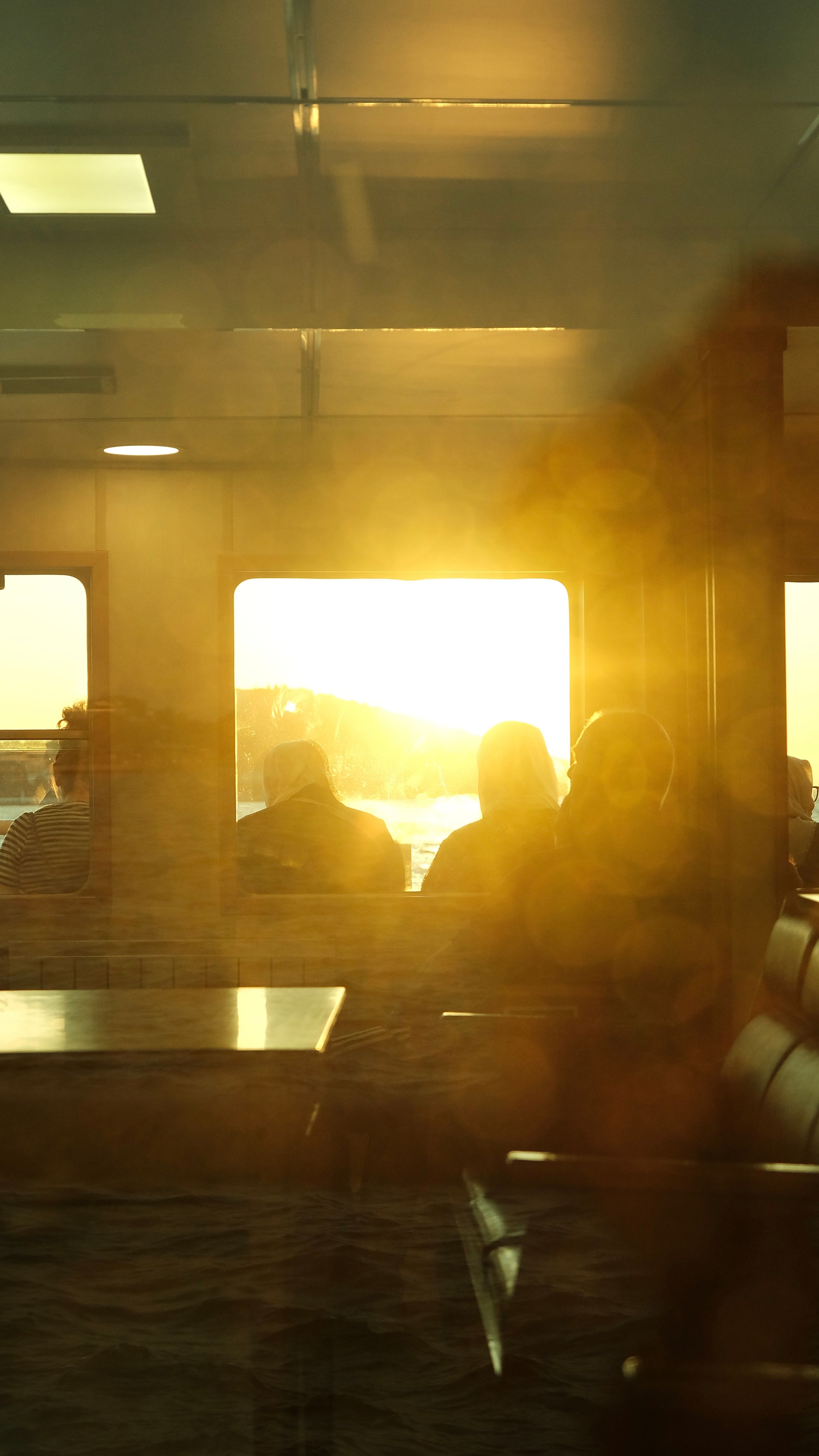 Passengers sit silhouetted against a vibrant sunset on a ferry ride.