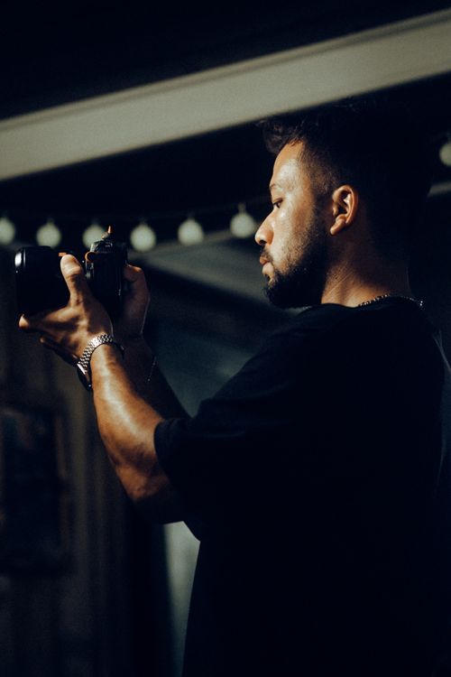 Free Side profile of a focused adult male photographer capturing an image indoors. Stock Photo