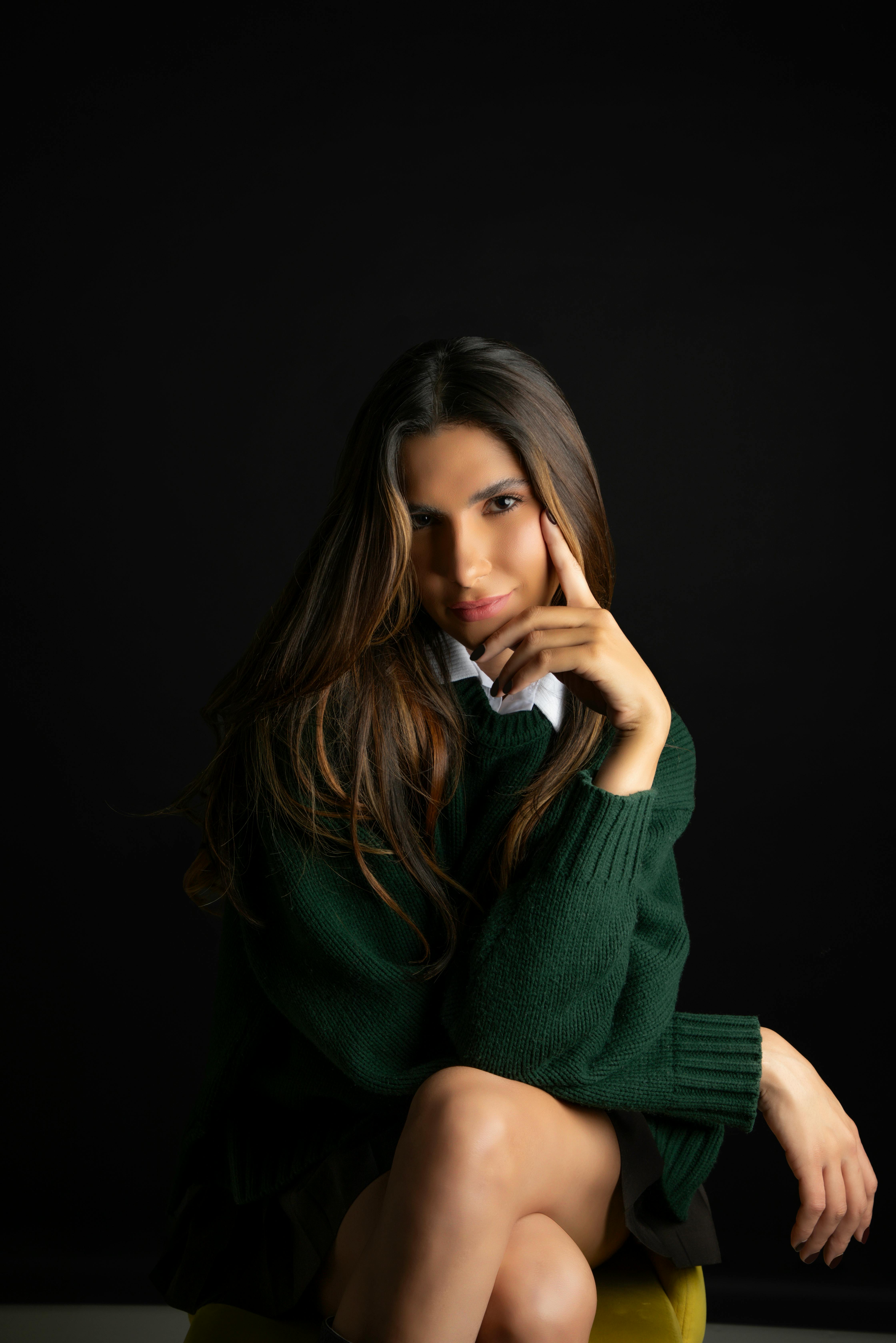 Artistic studio portrait of an elegant woman seated against a black background.
