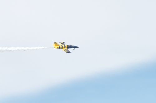 Free A vibrant yellow stunt plane performing aerobatics against a clear sky in Poprad, Slovakia. Stock Photo