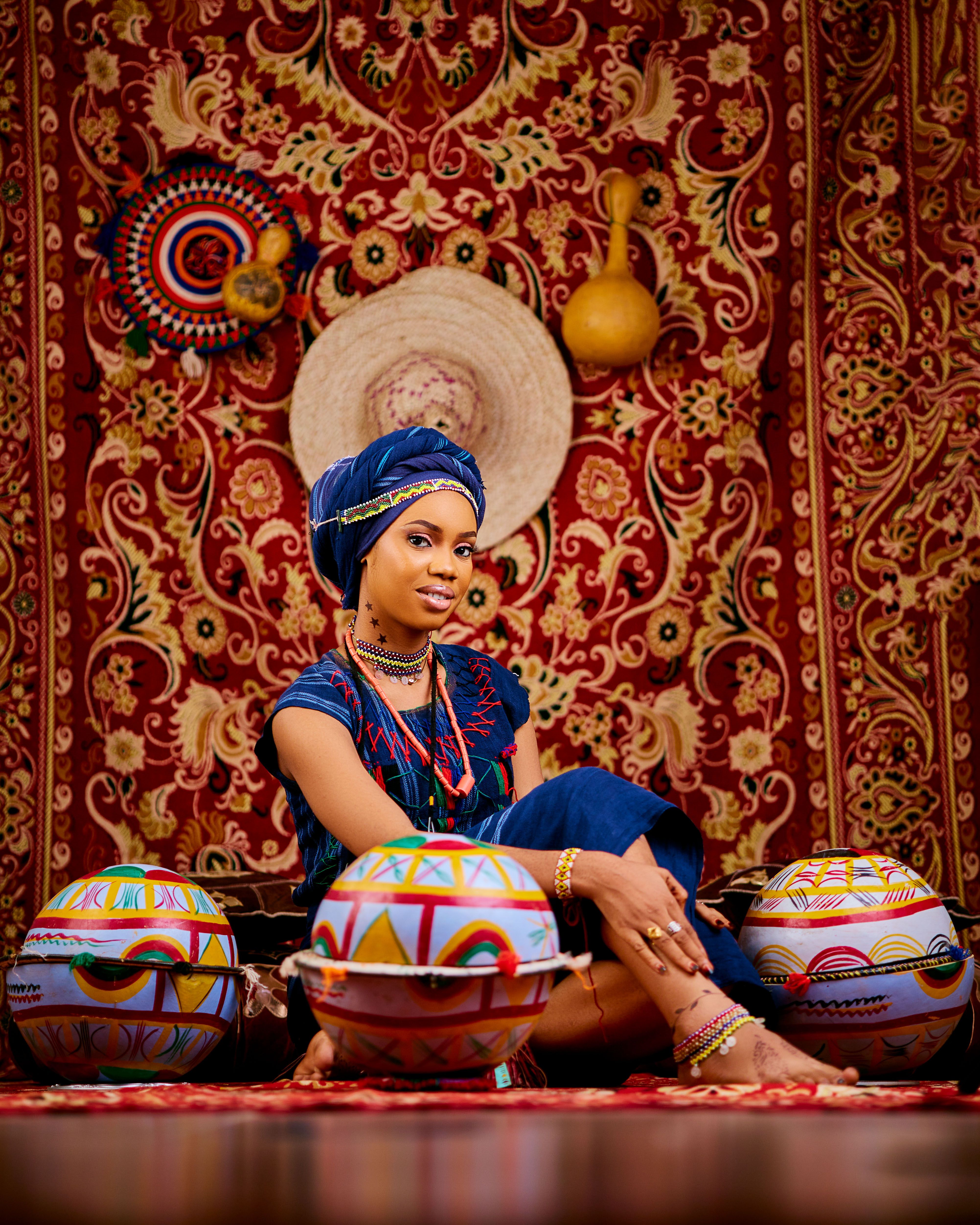 Vibrant portrait of a woman in African attire surrounded by traditional artifacts.
