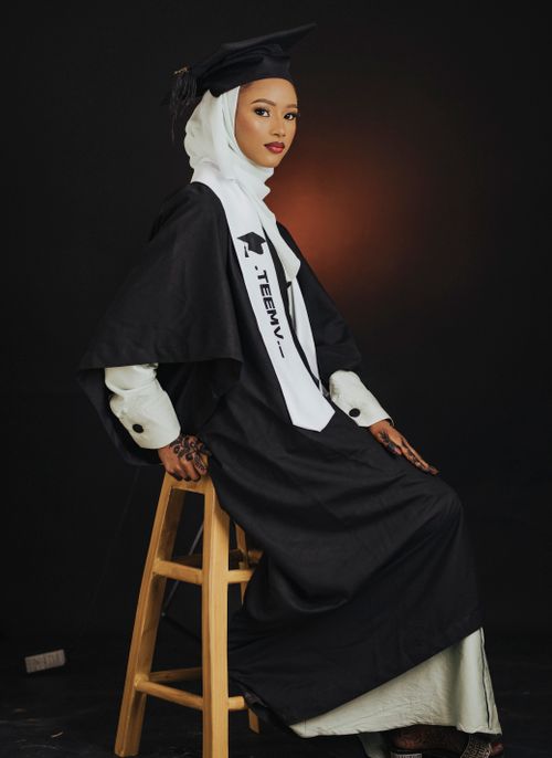 Free Portrait of a female graduate in academic regalia with a confident expression, wearing a hijab, highlighting diversity. Stock Photo