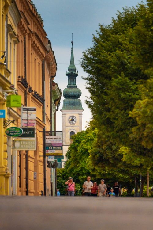 Free Scenic view of a European street with people and a historic clock tower. Stock Photo