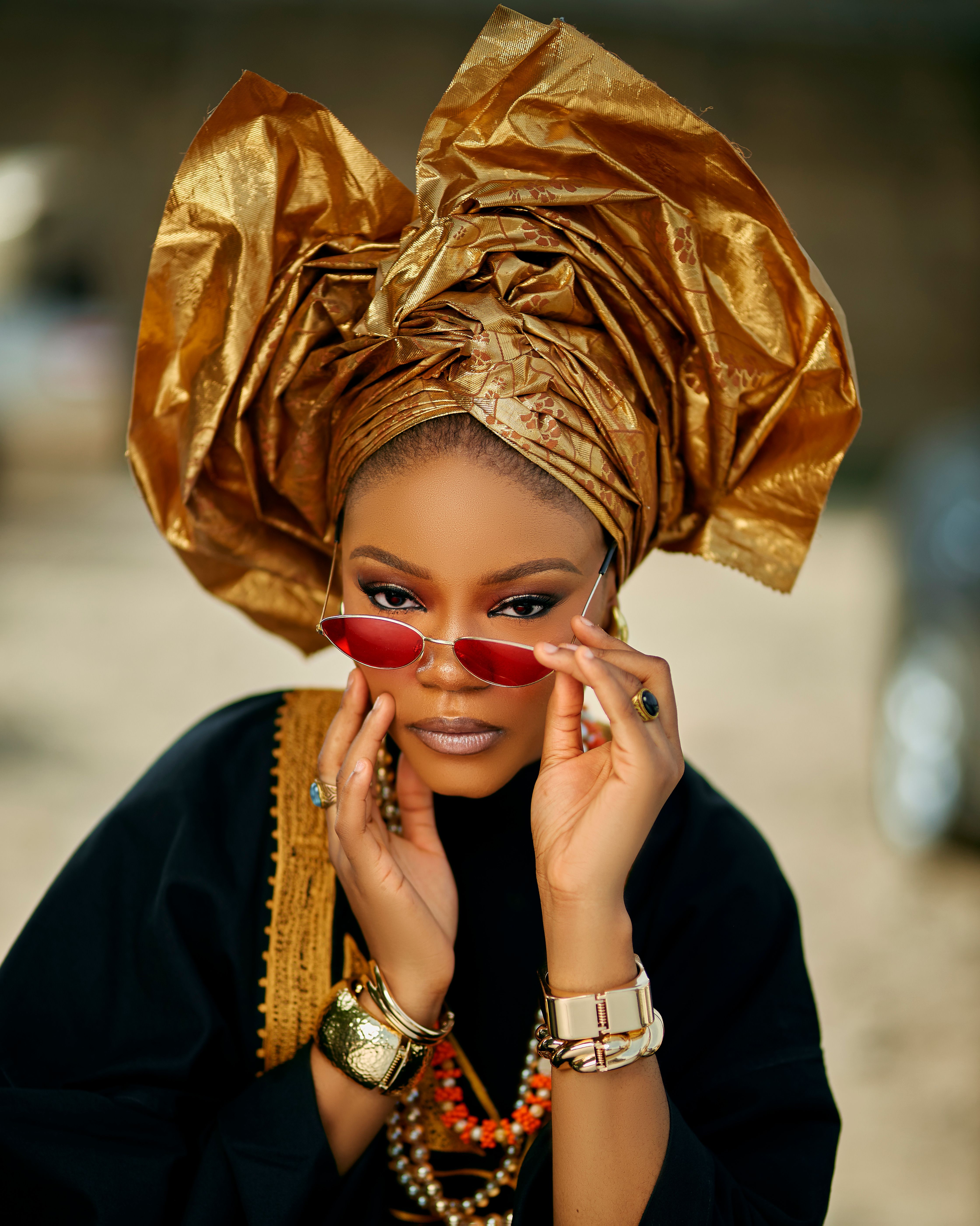 Stylish woman in African headwrap and sunglasses, showcasing cultural fashion.