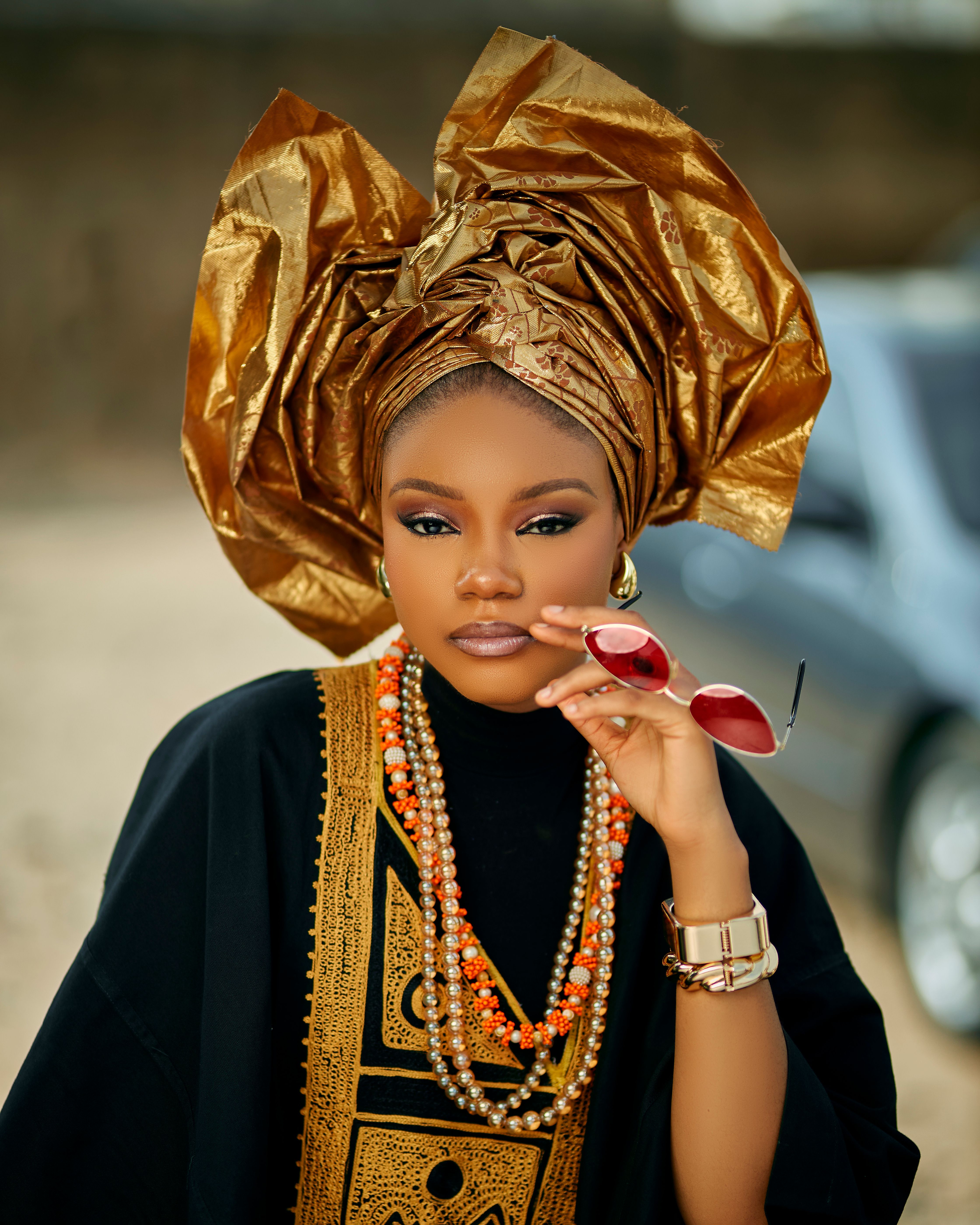 Stylish woman in Nigerian cultural clothing with vibrant headwrap outdoors.