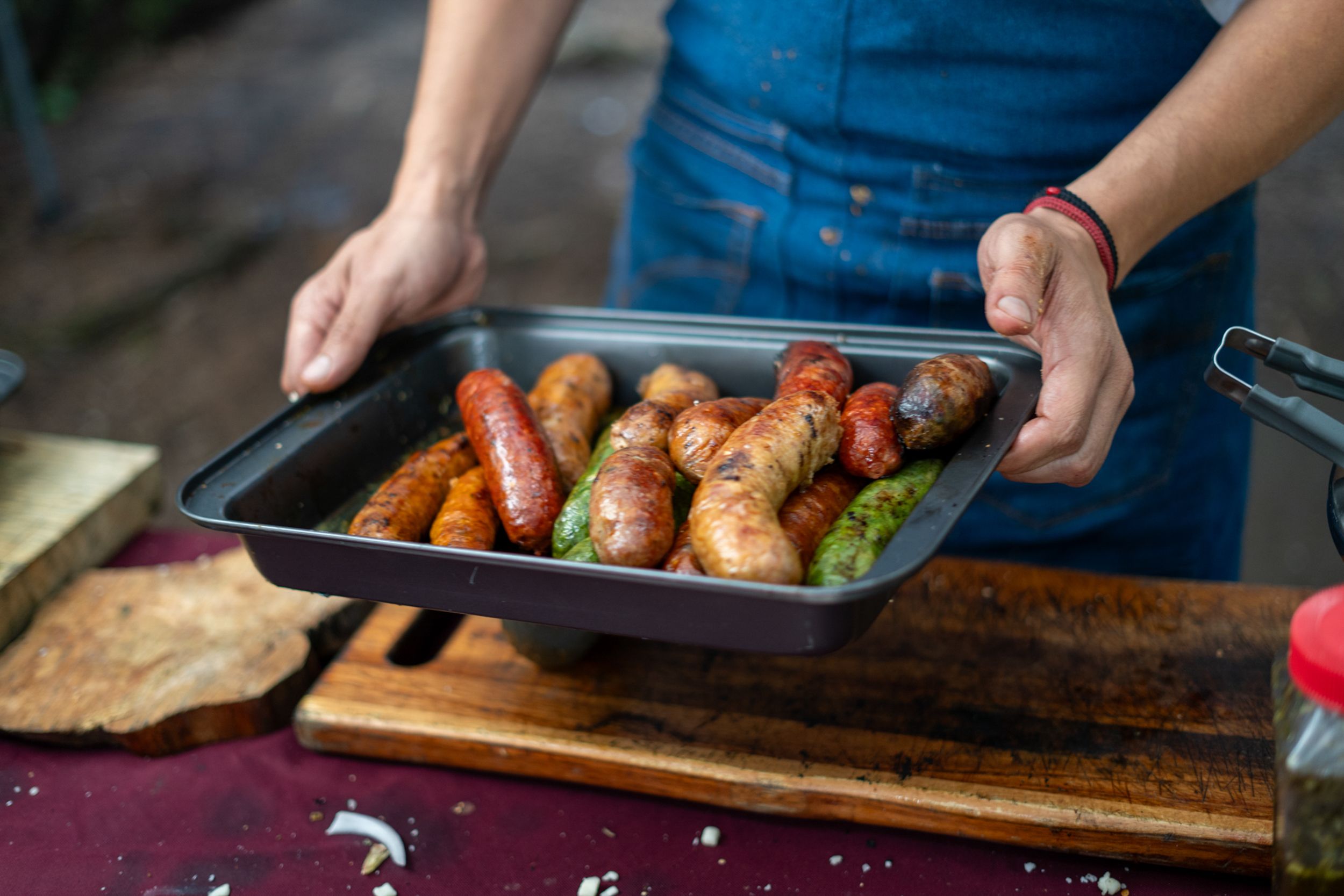 Delicious variety of grilled sausages in a tray held by a person ready for serving.