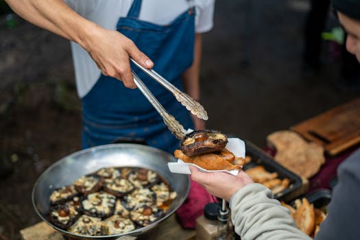 A street vendor serves a grilled portobello mushroom at an outdoor food market.