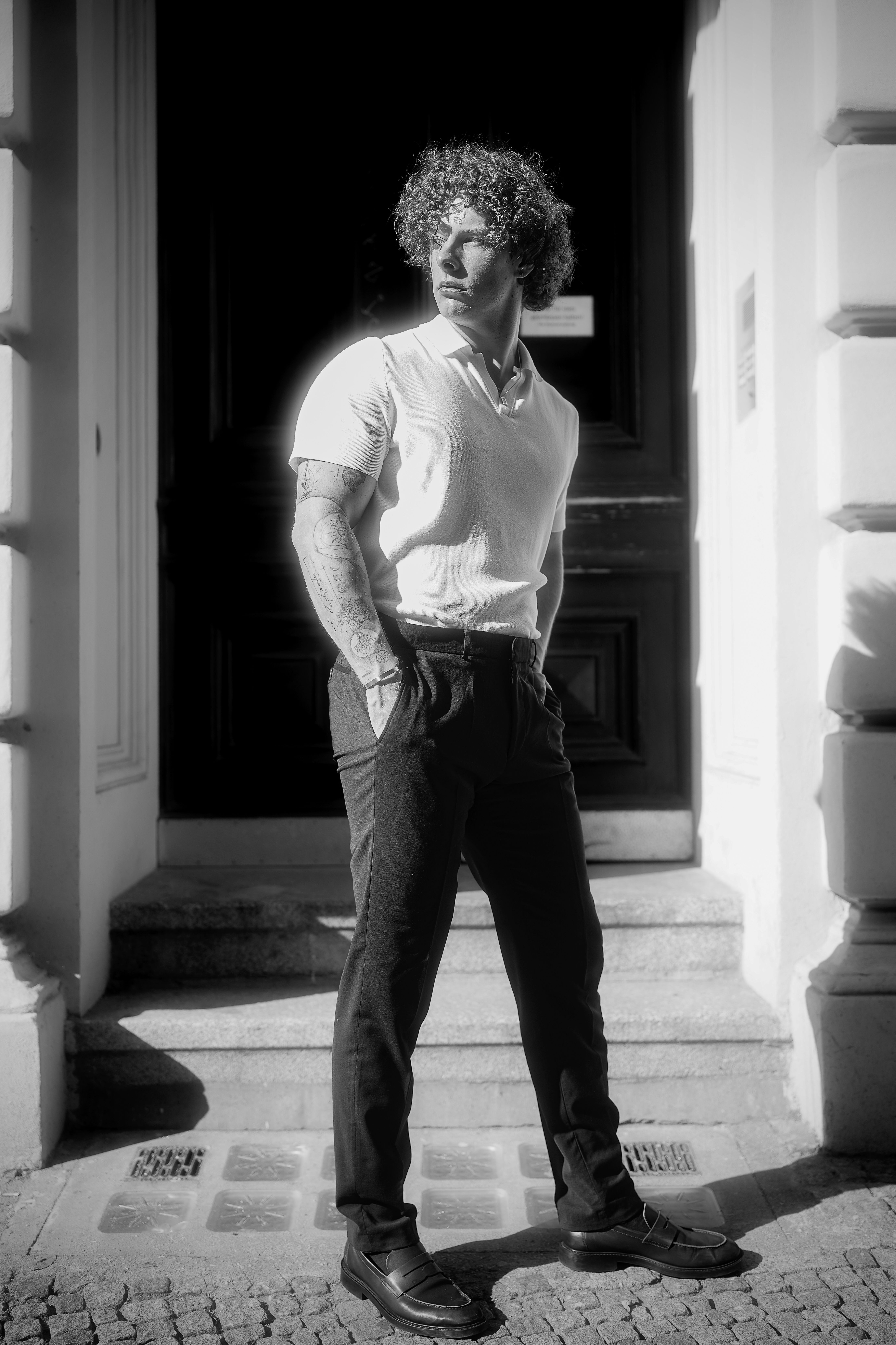 A fashionable man stands confidently in a black and white street setting.