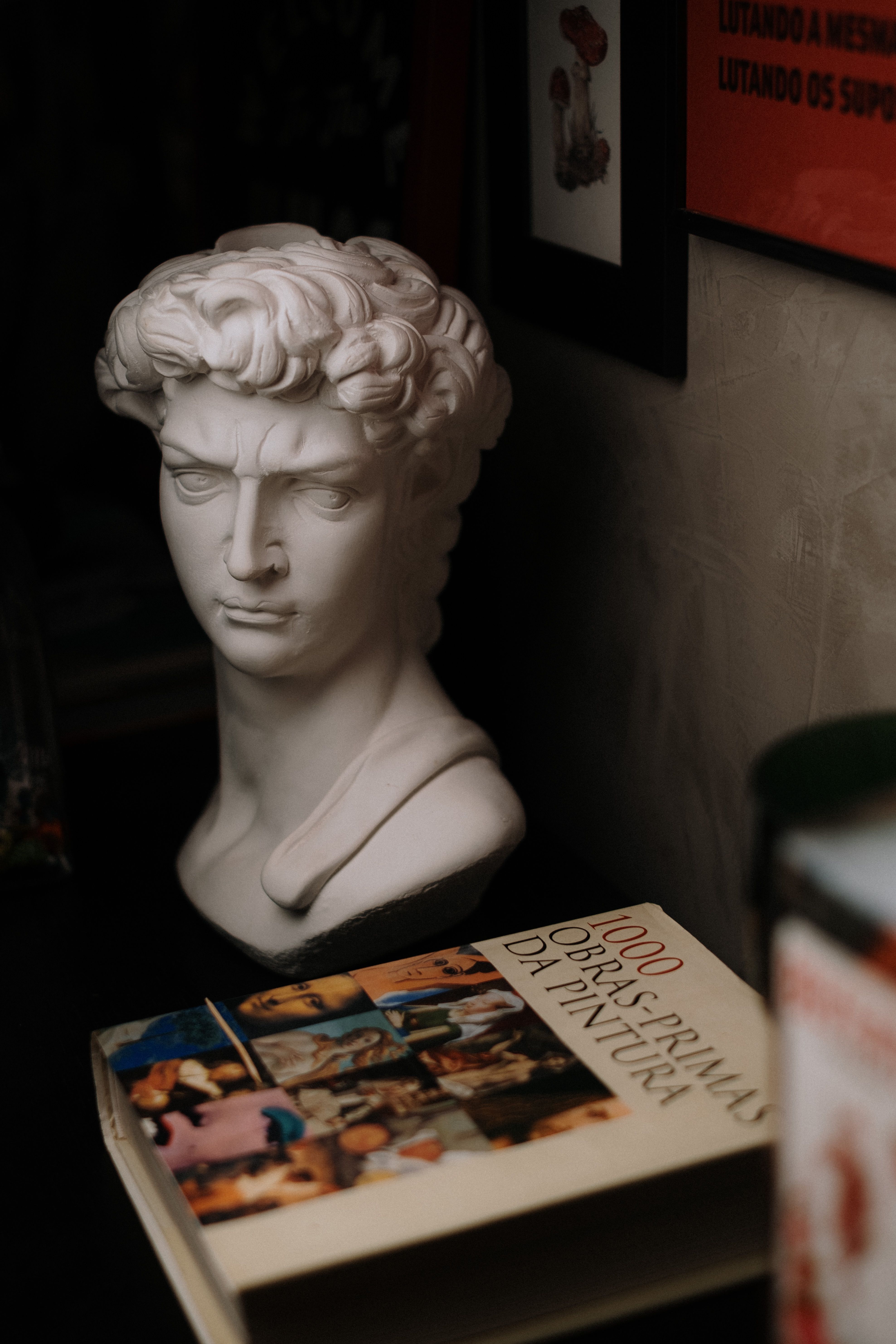 Bust of David sculpture beside an art book in soft lighting, creating a classic and artistic ambiance.