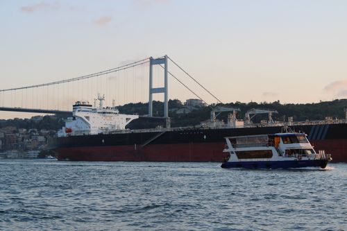 Free Bosphorus Bridge with passing ships in Istanbul at sunset, showcasing urban transport and stunning views. Stock Photo