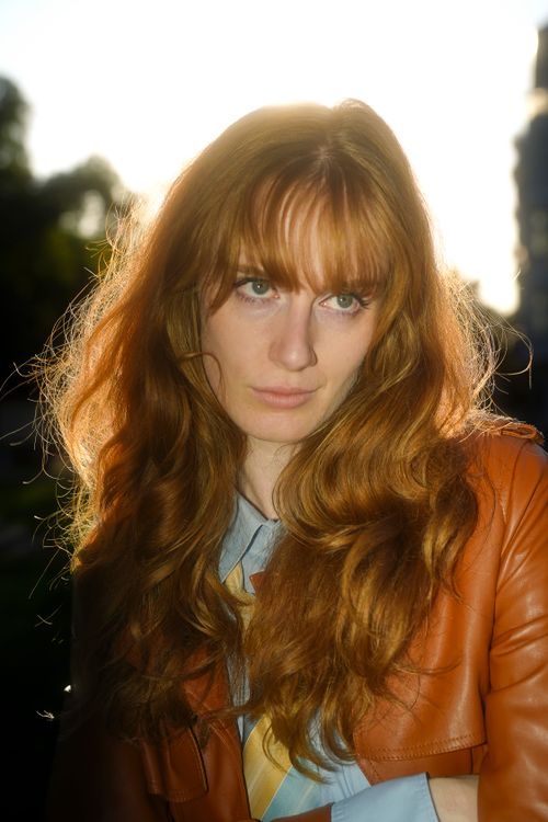 Free Portrait of a red-haired woman outdoors in warm sunlight, thoughtful expression. Stock Photo