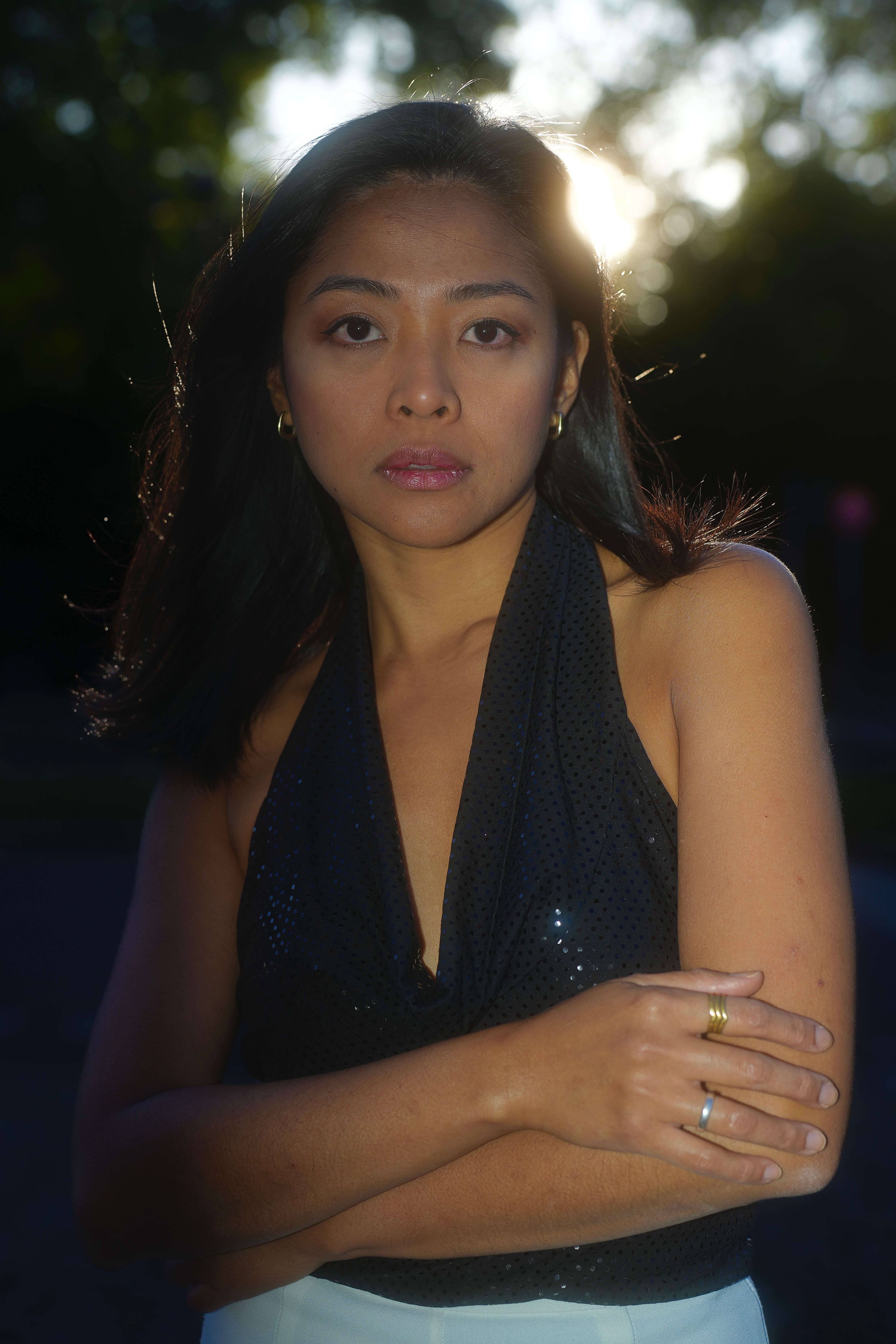 Confident woman in a halter top poses outdoors at sunset, radiating elegance.