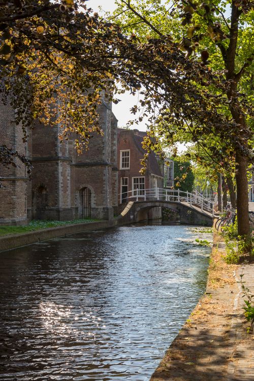 Free Peaceful canal view with a charming bridge and historic brick buildings in the background. Stock Photo