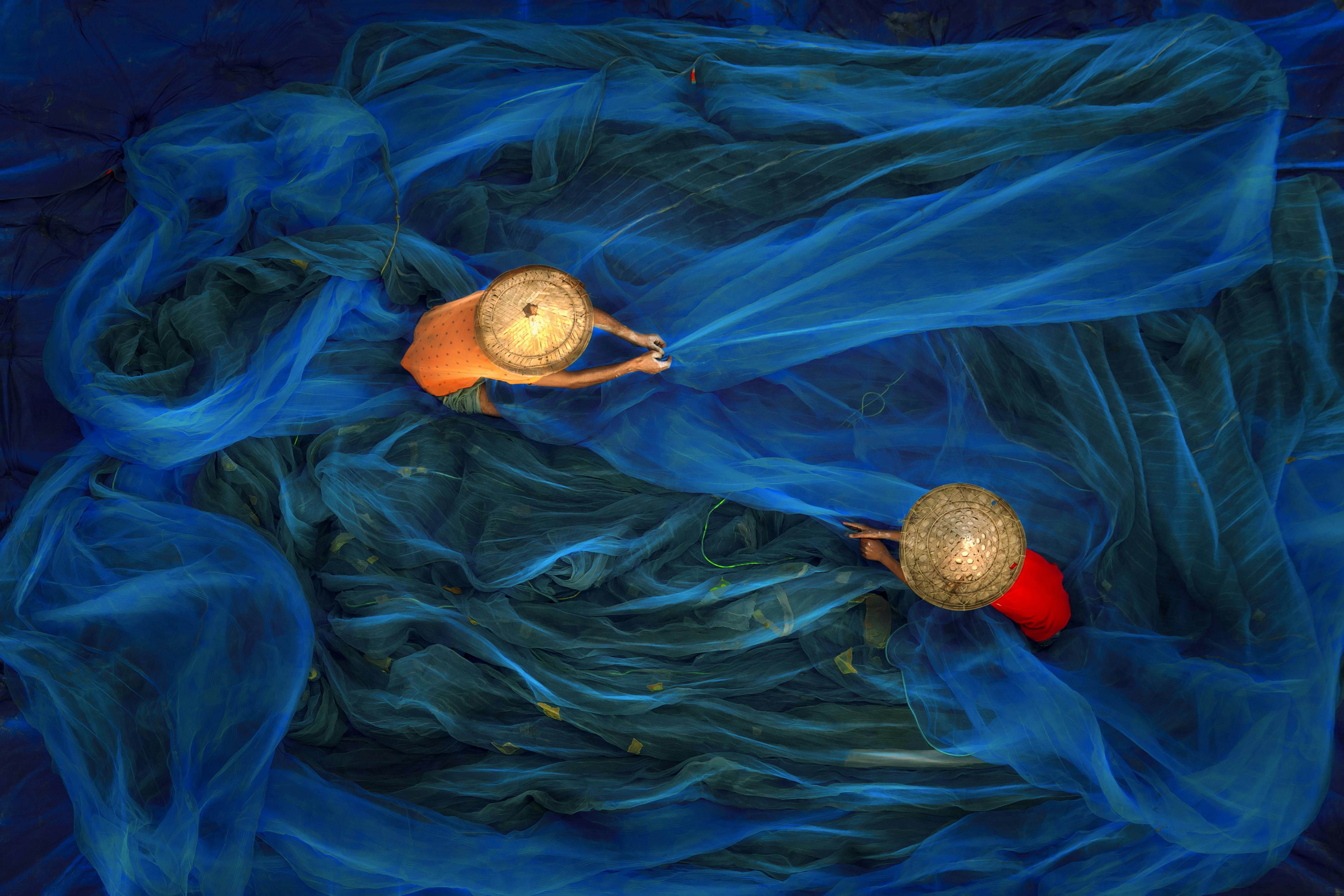 Aerial view of fishermen working with blue nets, showcasing tradition and teamwork, in West Bengal, India.