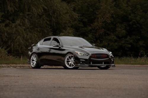 Free A stylish black sports car parked on an open road surrounded by greenery. Stock Photo