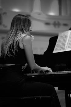Black and white image of a female pianist playing at a concert, focusing on musical expression.
