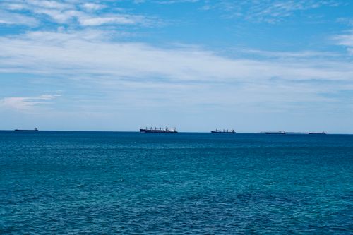 Free Multiple cargo ships floating calmly on the open sea under a clear blue sky. Stock Photo