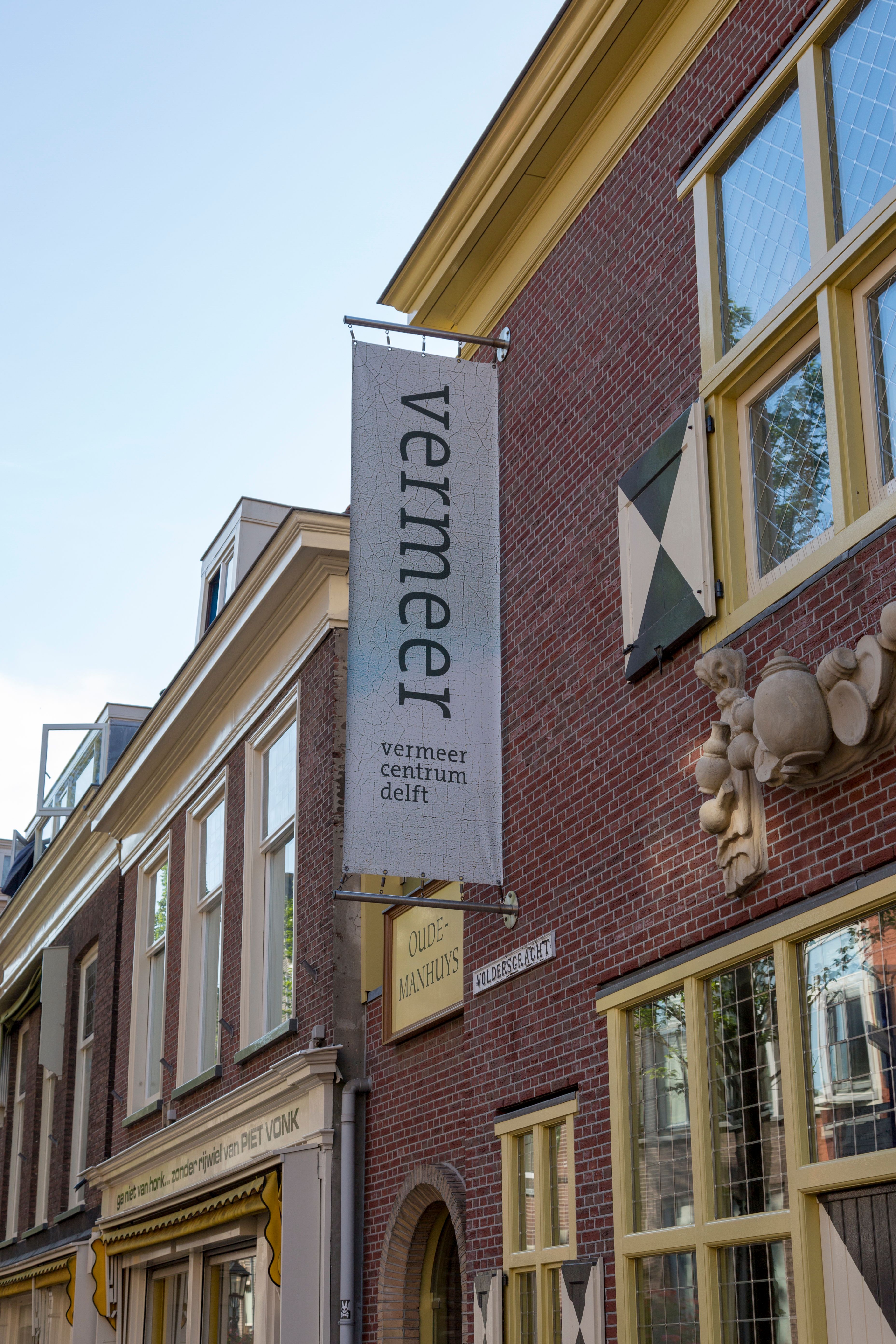 The Vermeer Centrum Delft as seen from the street, featuring a prominent sign and historic architecture.