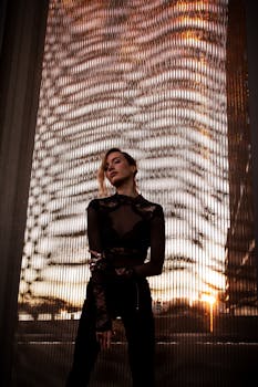 Elegant woman in lace outfit poses against Hamburg skyline during sunset, creating a dramatic effect.