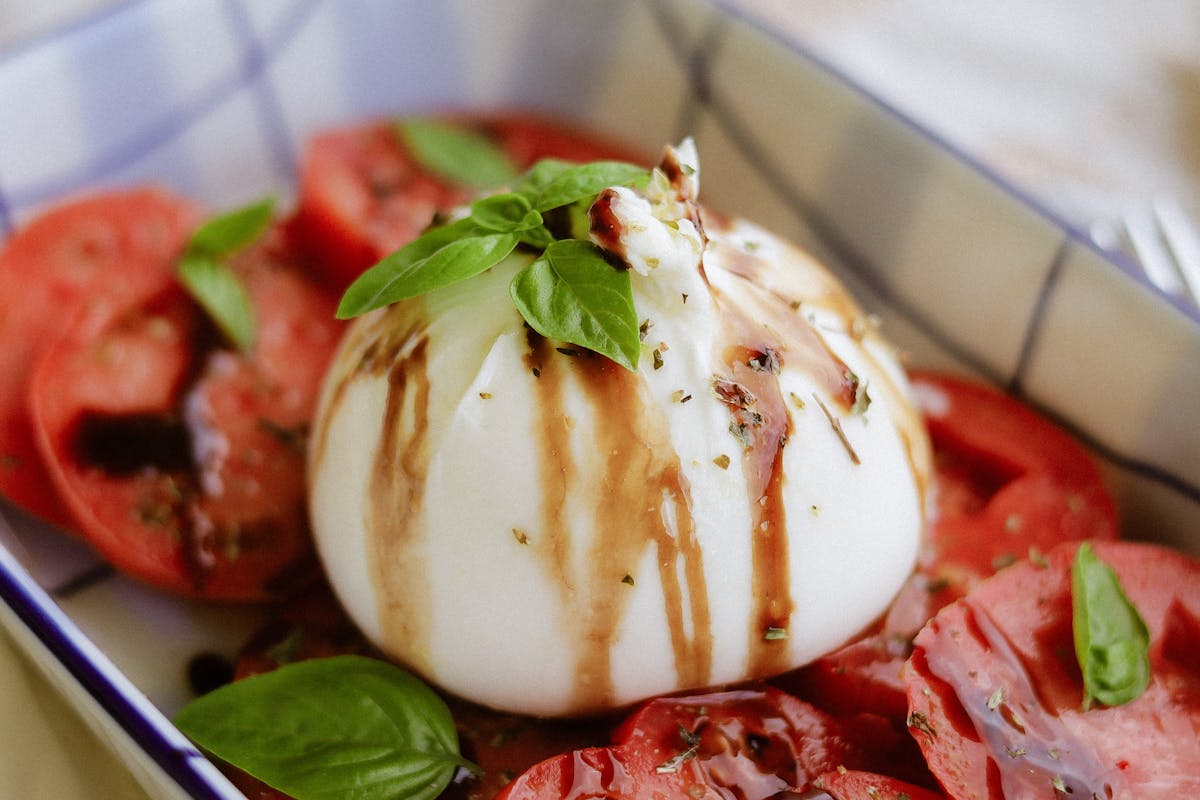 Insalata caprese con burrata cremosa, fette di pomodoro e foglie di basilico
