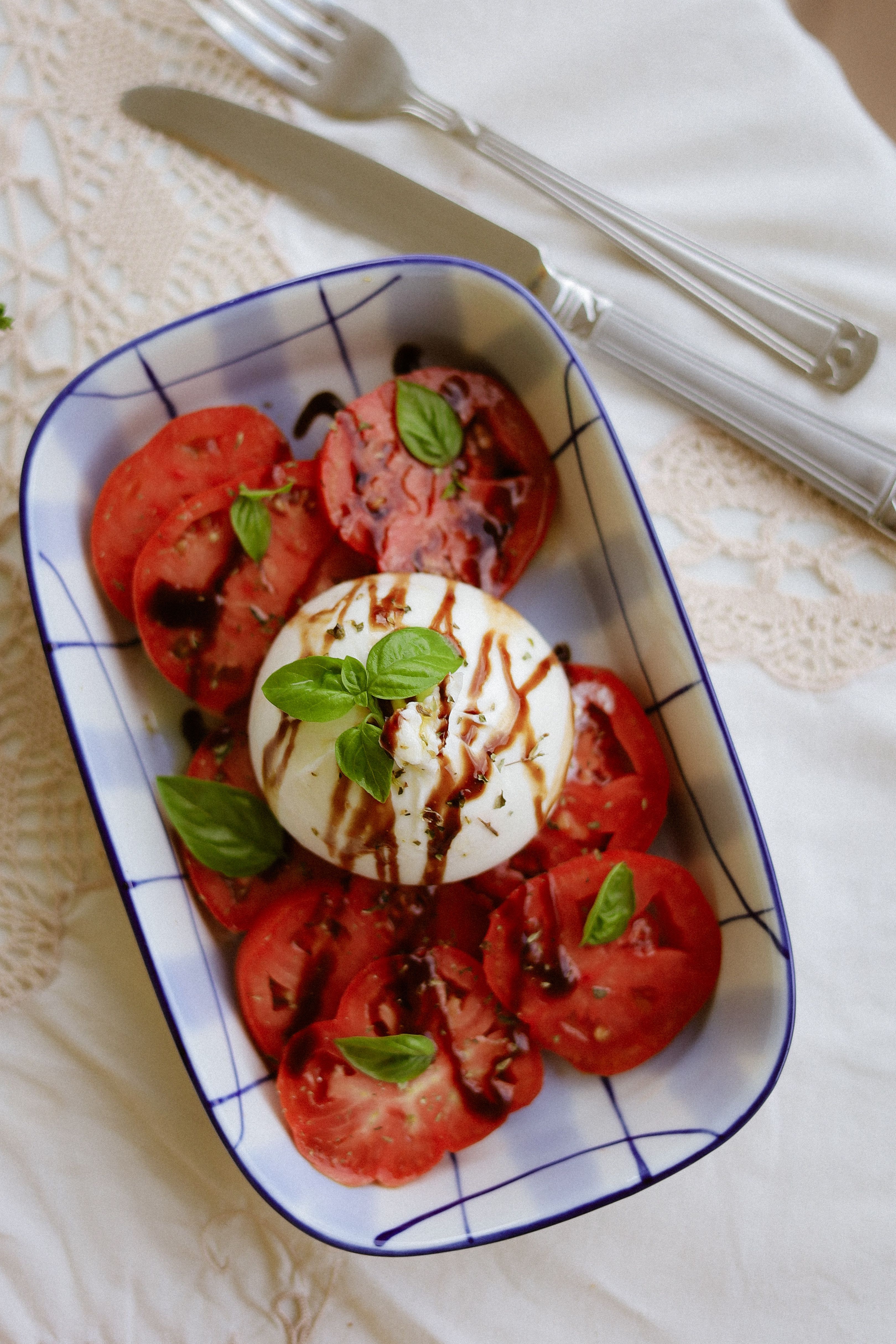 Caprese salad with burrata, tomatoes, basil, and balsamic glaze on a plate.