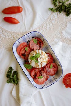 Appetizing Caprese salad with tomatoes, mozzarella, and basil, drizzled with balsamic.
