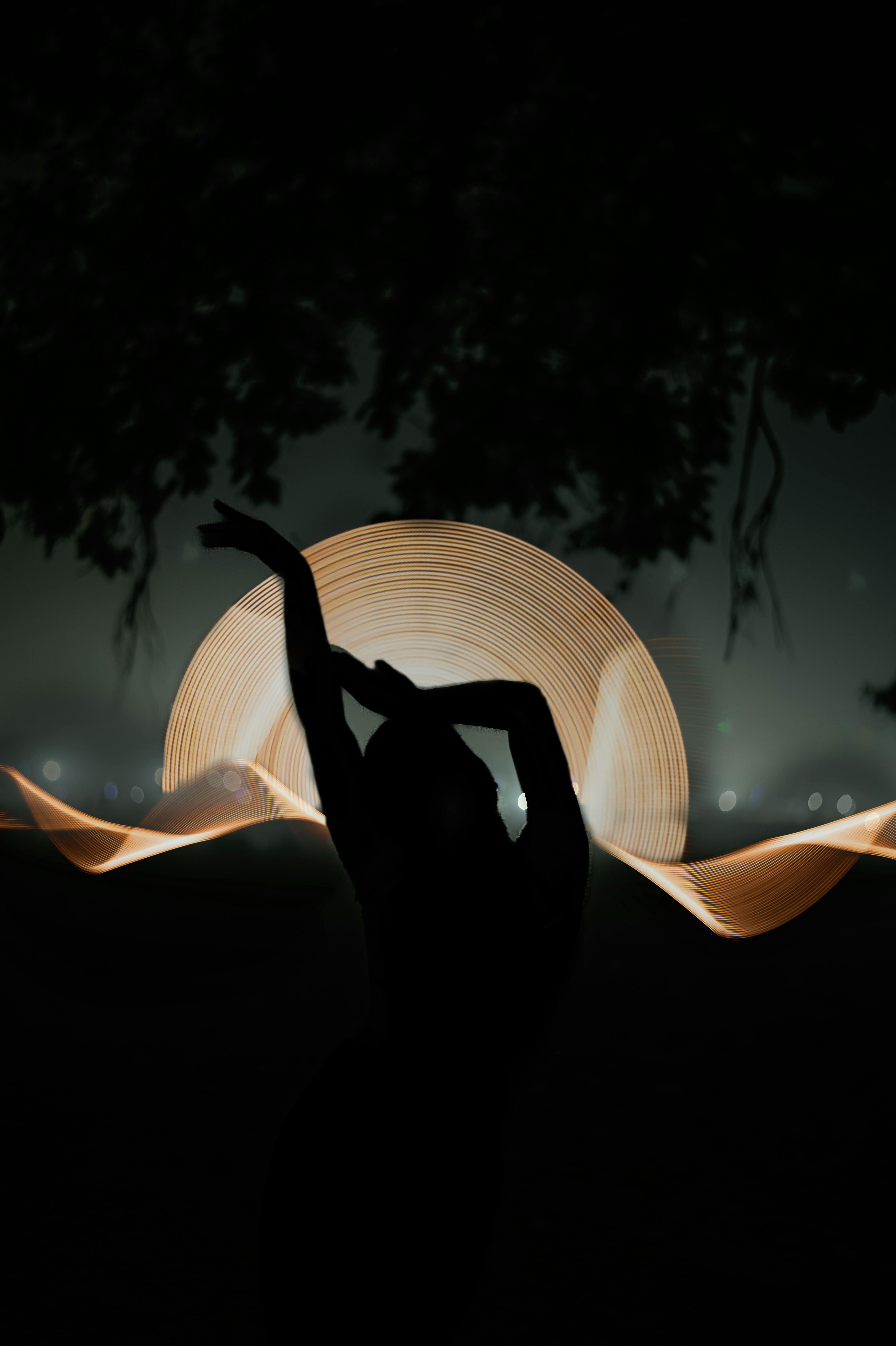 Artistic silhouette of a dancer with vibrant light painting creating a dynamic backdrop.