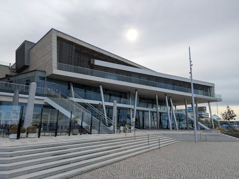 Contemporary architecture of a public building with a glass facade and open terrace in a cityscape.