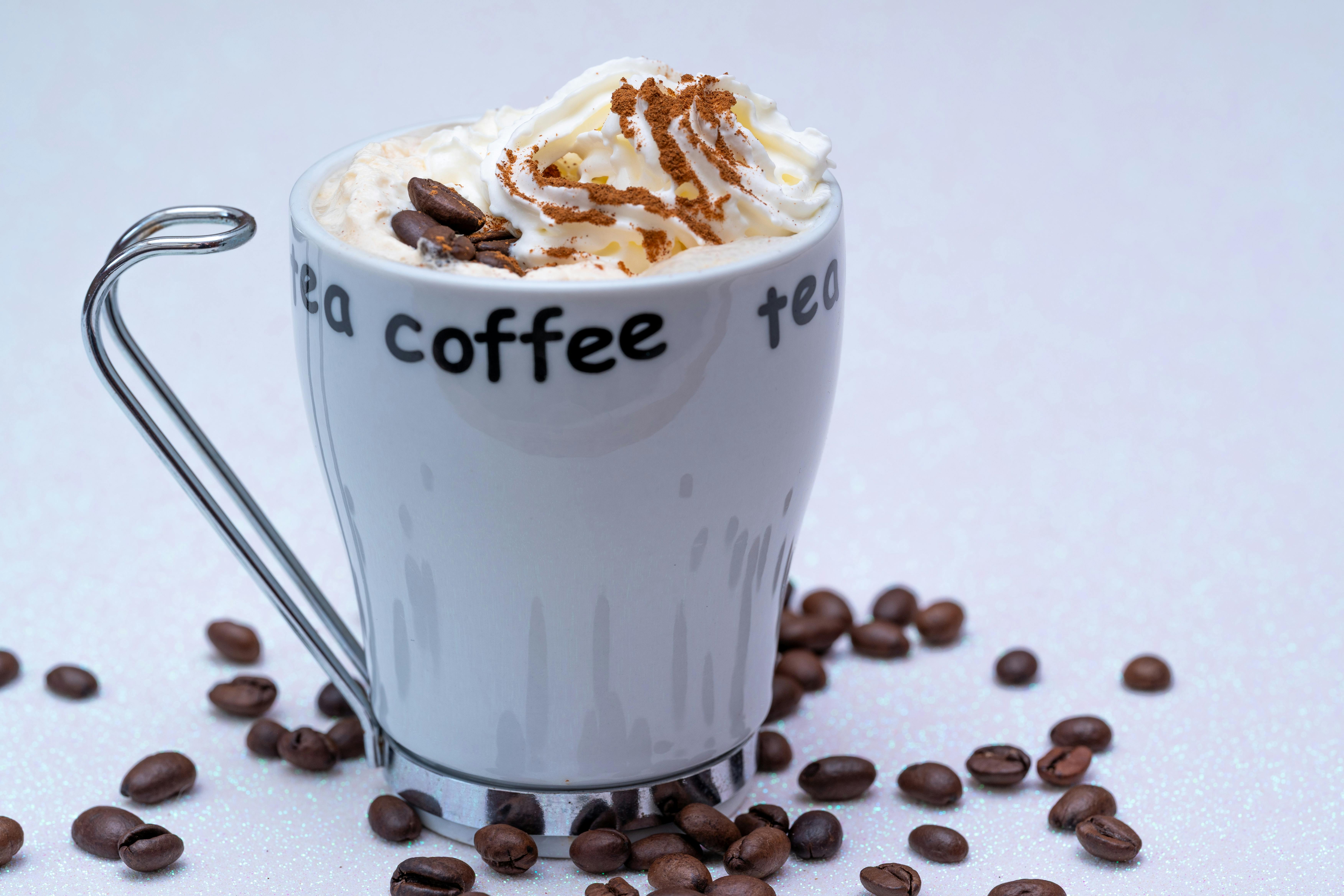 Şık bir fincanda dumanı tüten sıcak kahve, yanında taze kahve çekirdekleri ve huzurlu bir ortamda kahve keyfi detayı.